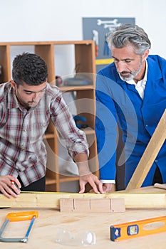 Two wood workers in carpentry measuring boards