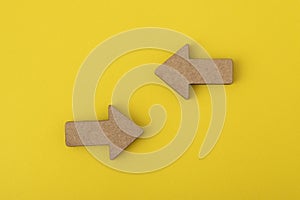 Two wooden arrows on yellow background. Direction signs. Copy space. Mock up