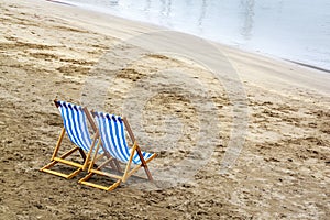 Two wooden beach chairs on the sand