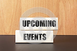 Two wooden blocks with the text UPCOMING EVENTS on a light wooden background