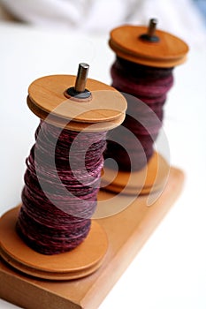 Two wooden bobbins with yarn