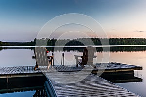 Two wooden chairs at Sunset on a pier on the shores of the calm Saimaa lakein Finland - 3