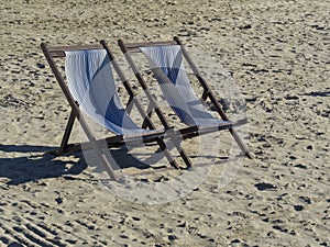 Two wooden deck chair on a sandy beach