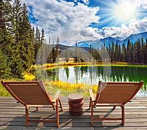 Two wooden deckchairs on the shore of lake