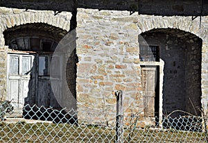 Two wooden doors, in the sun and in the shade, of a historic building in San Pellegrino in Alpe.