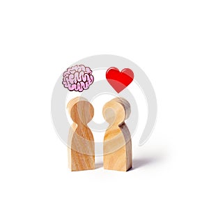 Two wooden figures with the image of the brain and heart. The balance between love and mind. Family versus career or work. Family