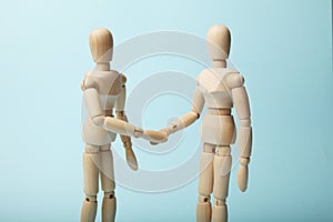 Two wooden figures of man shake hands