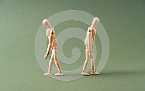 Two wooden figures walking away from each other on green background