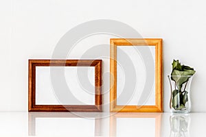 Two wooden frames with a white insert inside and a green one with a glass. Photo frame on a white wall background/
