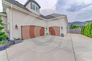 Two wooden garage doors with large driveways and concrete fence