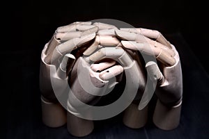 Two wooden hands clasped together while two other hands are girding them