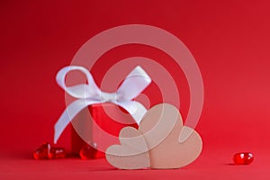 Two wooden hearts on a background of a red gift box and glass hearts on a red background. Valentine's day concept. Side