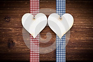 Two wooden hearts on dark wood planks