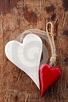 Two wooden hearts, red and white on old wood