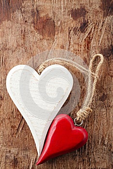 Two wooden hearts, red and white on old wooden background