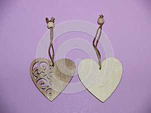 Two wooden hearts on a string on a pink textured background.