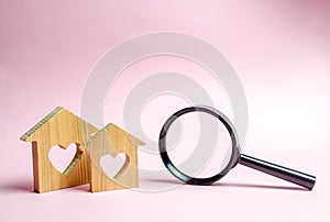 Two wooden house with a heart and a magnifying glass. The concept of finding affordable housing for young families and married