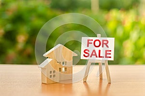Two wooden houses and a sign stand with the word SALE on the background of nature. selling a home. Sell real estate and property photo