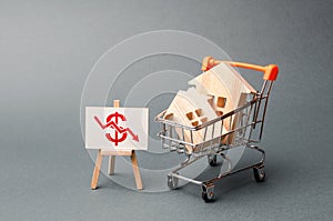 Two wooden houses in a trading cart and a stand with red arrow down. real estate value decrease. cheapening the rent or cost