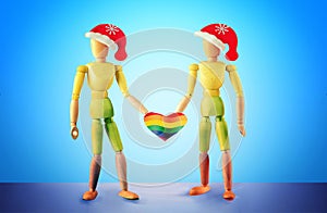 Two wooden mannequins representing a homosexual couple against the background of the pride flag, holding a heart with lgbt symbols