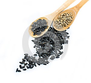 Two wooden spoons with black sunflower seeds and peeled seeds