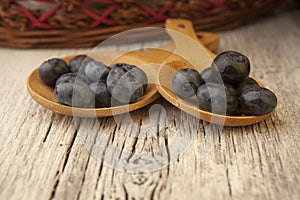 Two wooden spoons with fresh blueberries and wicker basket