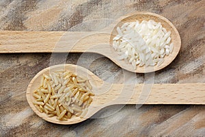 Two wooden spoons with white and brown rice grains