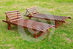 Two wooden sunbeds on the green grass lawn