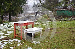 Two wooden table with autumn first snow in farm garden