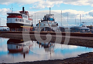 Two work boats dry docked under blue sky full of clouds, October 2018