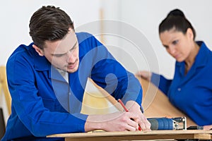 Two worker in blue dungarees in carpenters workshop