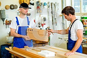 Two worker with cardboard in a carpenter's workshop