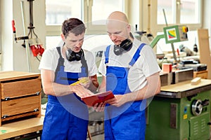 Two worker in a carpenter`s workshop in conversation