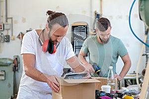 Two worker in a carpenter`s workshop with parcel