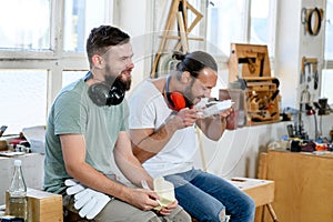 Two worker in a carpenter`s workshop taking a break