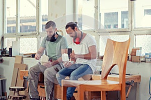 Two worker in a carpenter`s workshop taking a break