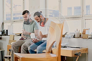 Two worker in a carpenter`s workshop taking a break