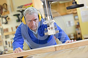Two worker in carpenters workshop using saw machine