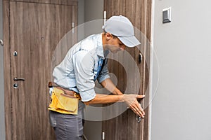 Two worker hands of carpenter at lock installation into wood door