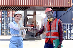 Two worker wear safety helmet fist bumping hands after complete work at logistic shipping cargo containers yard. African engineer