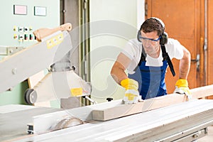 Two worker in workshop using saw machine
