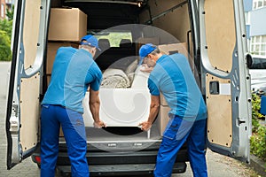 Two Workers Adjusting Sofa In Truck