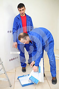 Two workers in blue clothes prepare for paintind photo