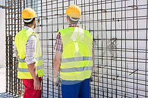 Two workers checking the durability of the steel structure of a