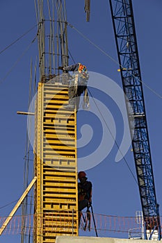 Two workers in a construction hanging in a column