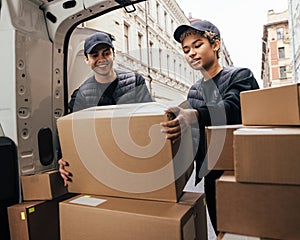 Two workers of delivery company loads cardboard boxes into a van