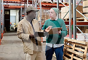 Two workers discussing delivery in warehouse