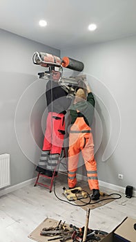 Two workers drill a hole in wall, diamond drilling. Preparation for installation of Heat Exchangers - Recuperator