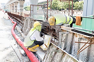 Two workers fitting wooden mould onto rebar at construction site