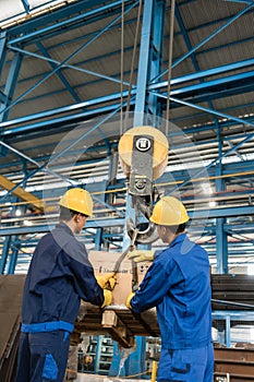 Two workers handling heavy loading lifted by crane